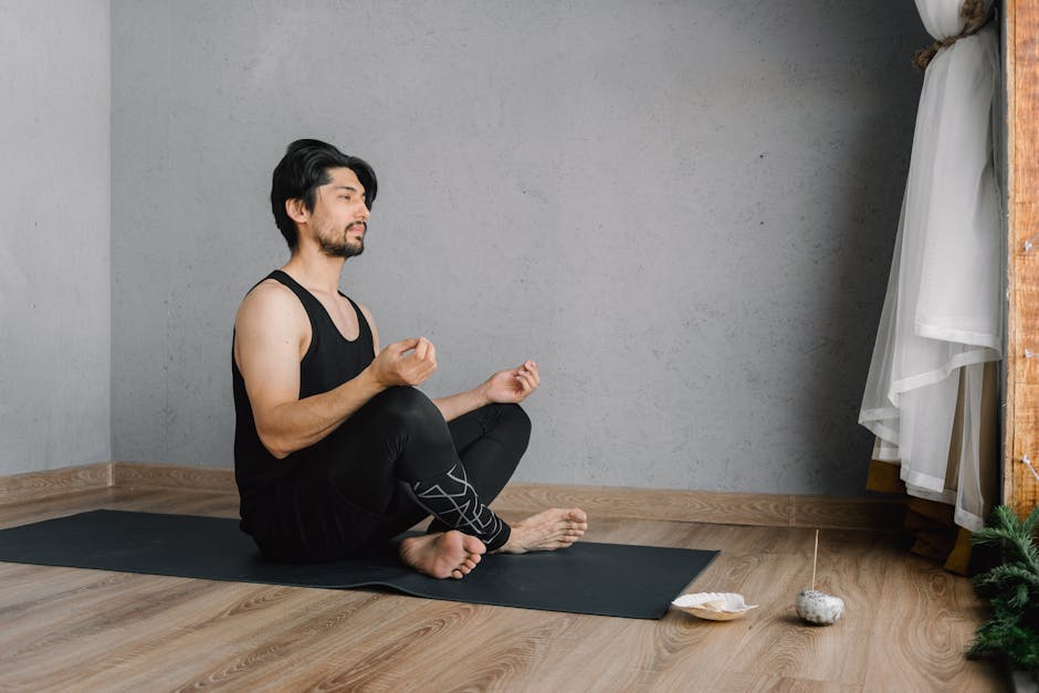 Man sitting cross-legged on a yoga mat in a bright, modern living room.